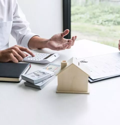 Conseiller immobilier présentant un financement à une cliente lors de la signature d’un contrat.