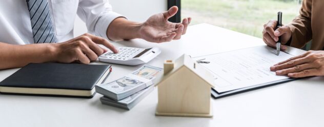 Conseiller immobilier présentant un financement à une cliente lors de la signature d’un contrat.